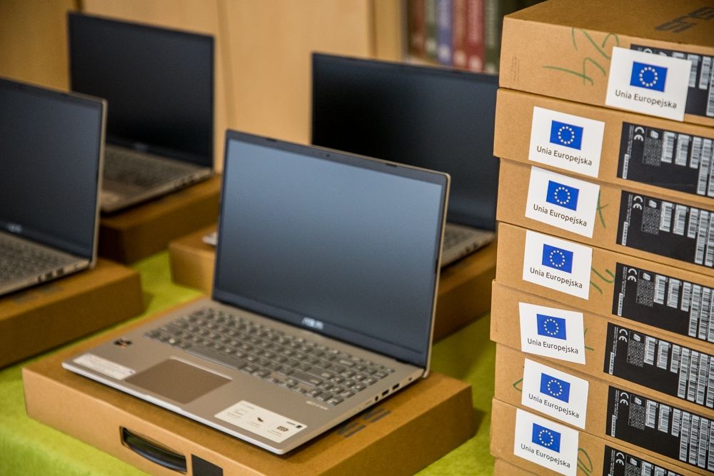laptop, po prawej stronie pudełka z naklejkami unii europejskiej